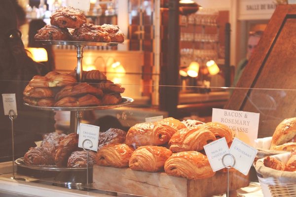 The pastry case glowing in early-morning light, croissants and pastries with small handwritten labels.