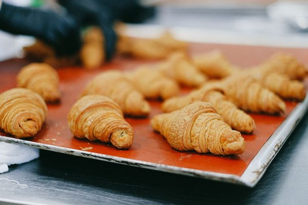 Golden croissants lined up on a baking tray.