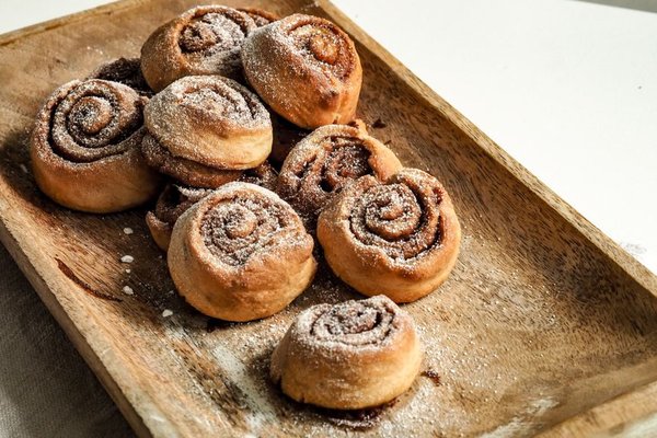 Sugared cinnamon rolls piled on a wooden board.