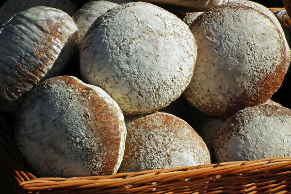 Flour-dusted boules heaped in a basket.