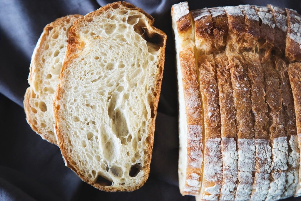 A sliced country loaf on a dark cloth.