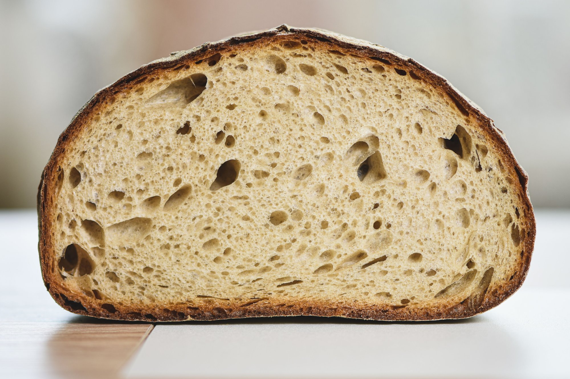 A sourdough loaf cut in half, showing an open, airy crumb inside a dark crust.