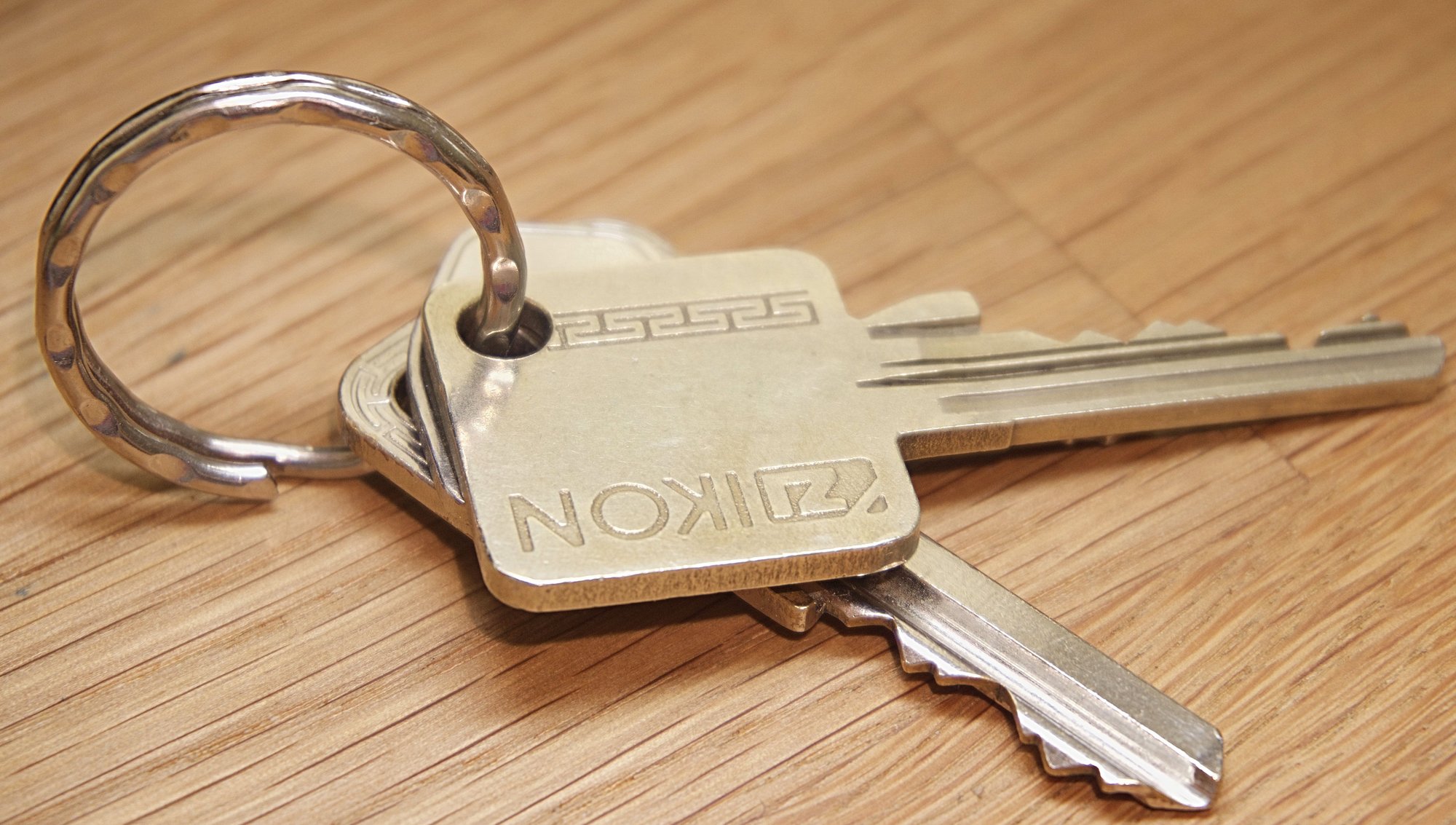 A ring of house keys lying on a wooden bench.