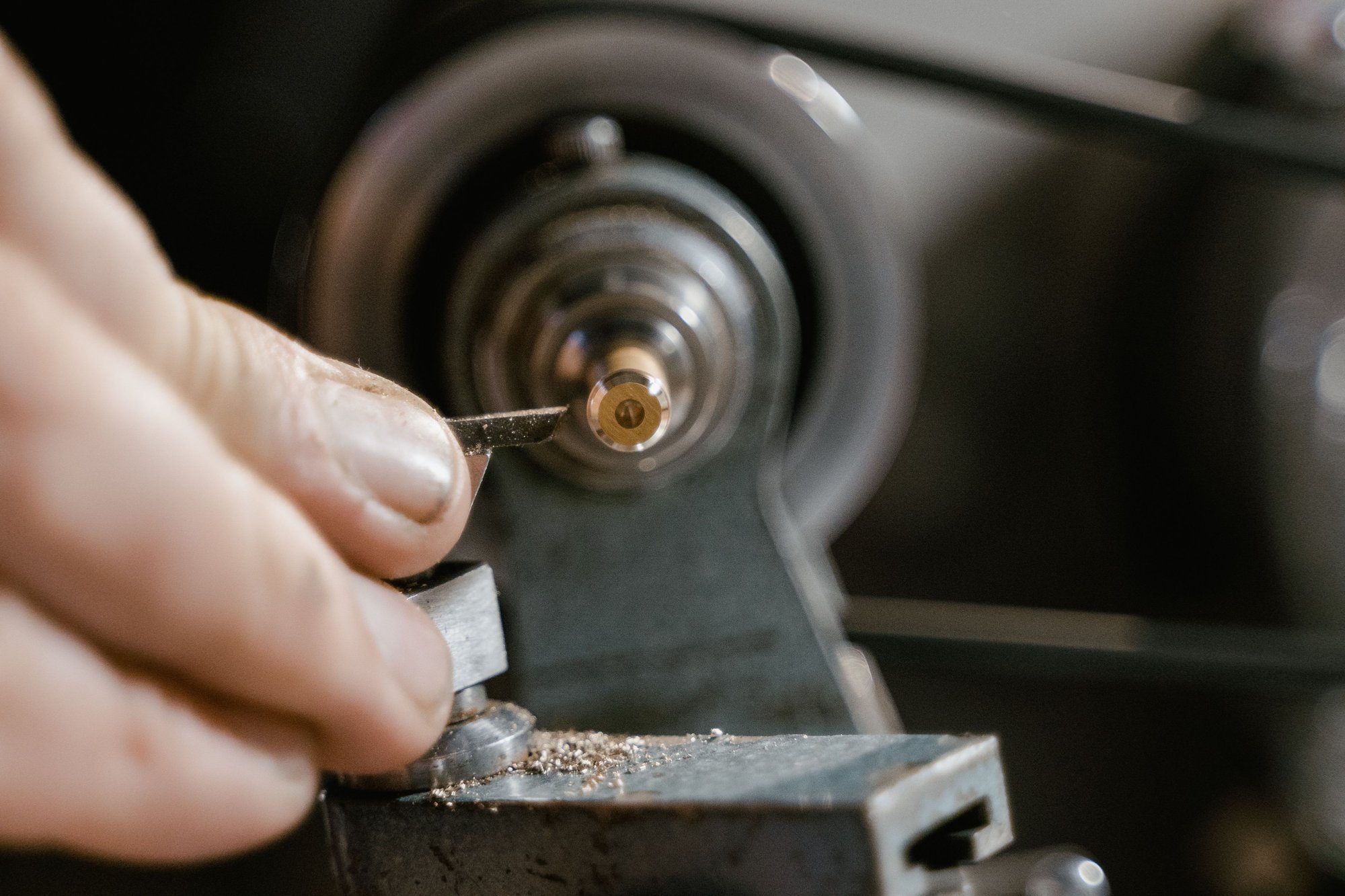 A locksmith’s hands guiding a key blank through the cutting wheel of a key machine.