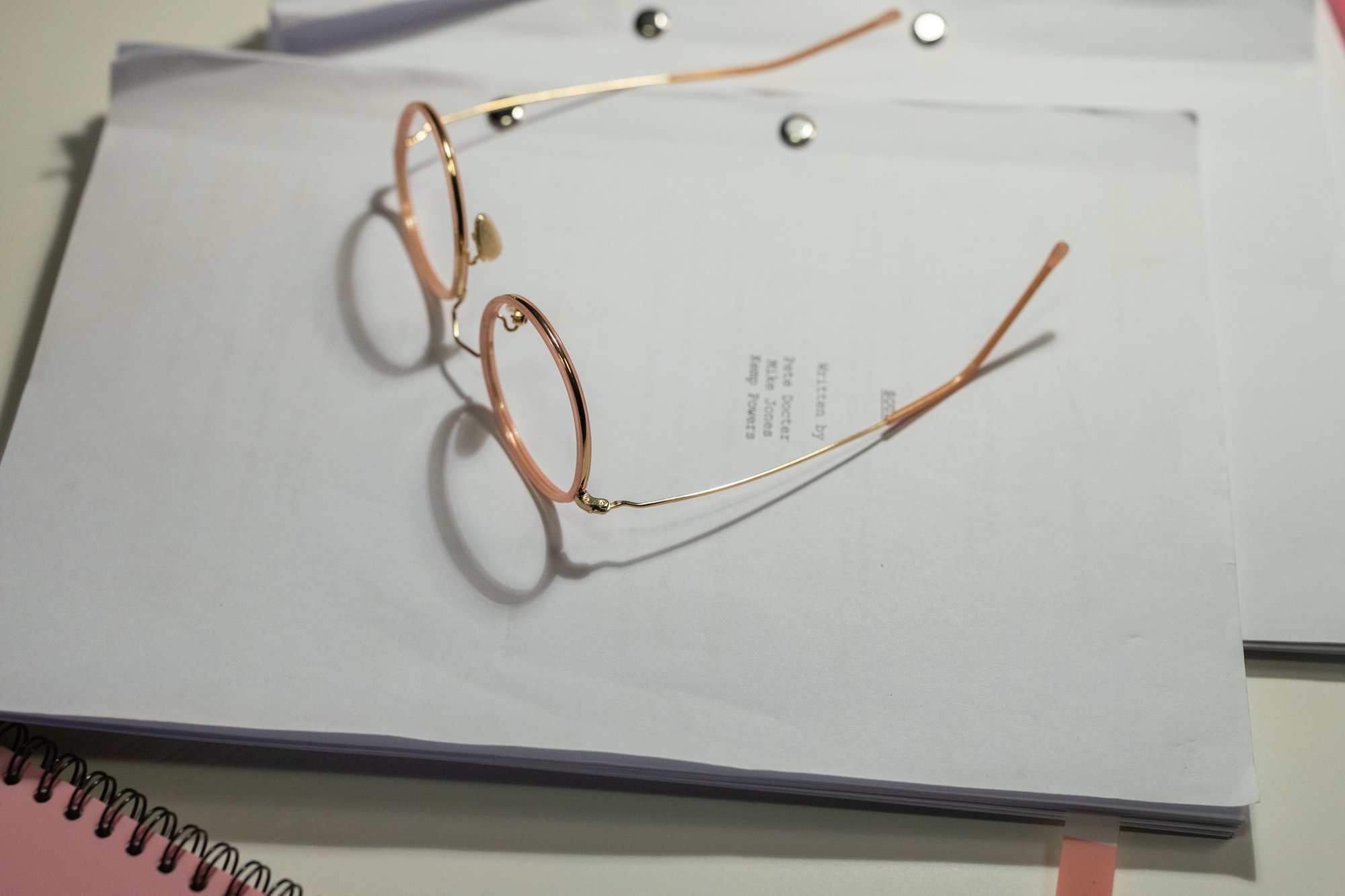 Reading glasses resting on a stack of typed documents.