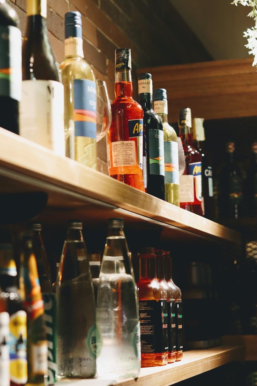 Bottles ranked along the original pharmacy shelving, lit warm against dark wood.
