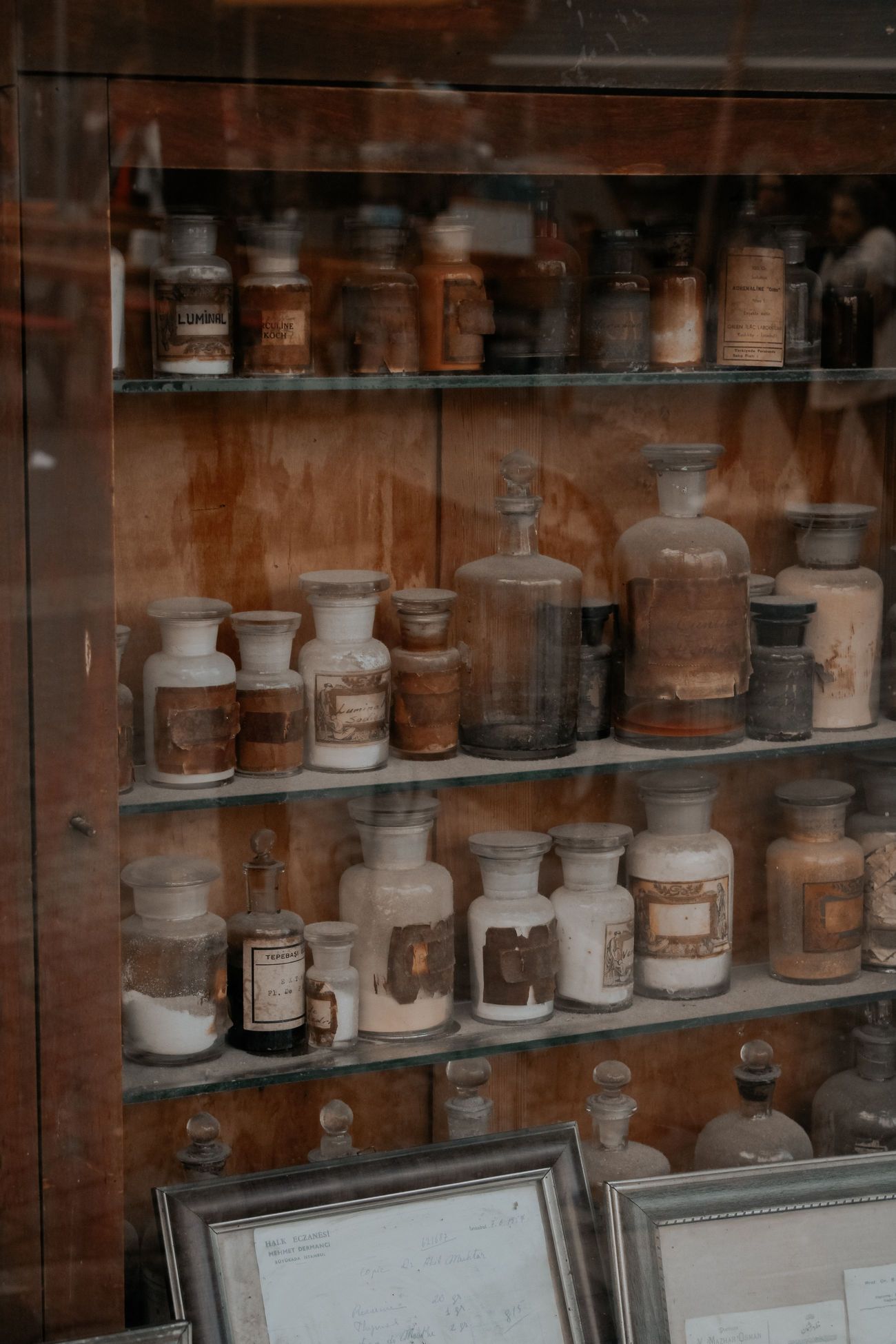 An antique apothecary cabinet behind glass, shelves of labelled ceramic and glass jars in rows.