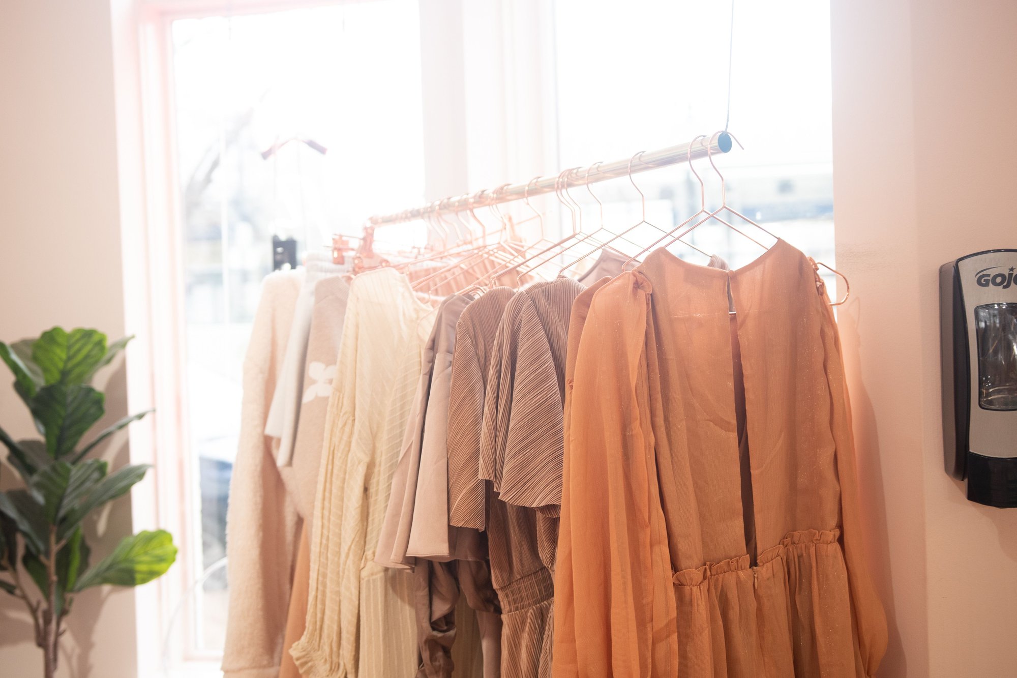 A rail of garments on wooden hangers in warm light.